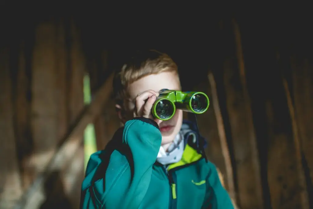 Young boy looks into the future with binoculars field glasses.